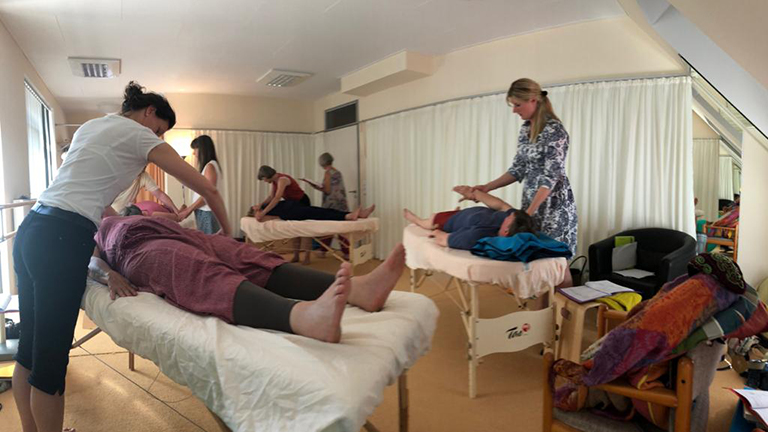 Vayana heiler- & Intuitionstrainer Ausbildung - Seminarraum mit Behandlungsliegen und Teilnehmer beim Arbeiten